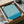 May include: Framed poster with flowing teal and cream wavy lines in an optical illusion pattern, displayed in black frame inside cardboard shipping box with protective packaging. Text reads "BAUHAUS AUSSTELLUNG Juli - Sept. 1923" in bottom corner. Surrounded by white tissue paper and brown packing materials on light surface.