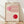 May include: Framed Bauhaus-style poster with geometric design featuring red and pink circular forms intersected by curved parallel lines on cream background, displayed in light wood frame against white wall on wooden floor with natural lighting shadows