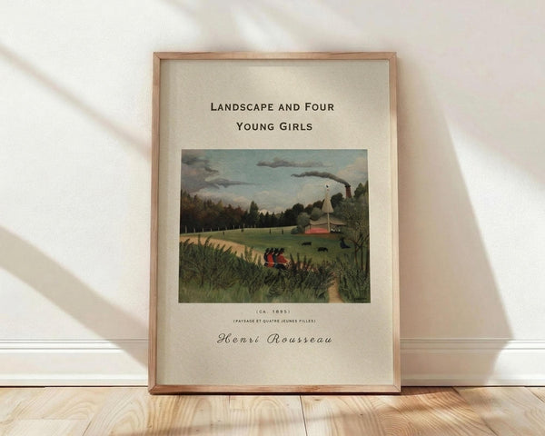 May include: Framed art print featuring Henri Rousseau's 1895 pastoral landscape painting with four young girls in a green countryside scene, displayed in light wooden frame against white textured wall on wooden floor with natural window light creating soft shadows