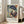 May include: Framed art print featuring a woman in a blue hat and floral dress in Matisse's colorful style, displayed against white wall next to beige sofa with natural lighting from nearby windows creating soft shadows on hardwood flooring.