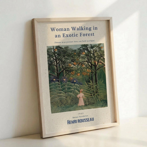 May include: Framed art print leaning against white wall showing Henri Rousseau's jungle painting with lush green tropical foliage and small figure in pink dress walking through dense forest. Print has cream background with black text title and artist name. Light wooden frame casts soft shadow on white surface below.