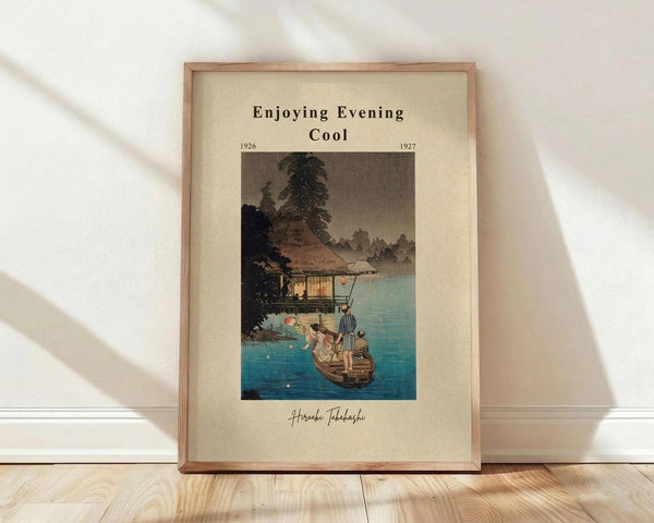 May include: Framed vintage Japanese woodblock print showing evening lakeside scene with traditional thatched-roof house, small boat with figures in striped clothing on blue water, surrounded by dark trees. Cream matting with black text reading "Enjoying Evening Cool" and dates 1926-1927. Natural wood frame leaning against white wall on light wooden floor with soft shadows.