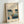May include: Framed vintage Japanese woodblock print featuring boats with white sails on blue water under evening sky with full moon. Print shows traditional fishing vessels and smaller boat with figures. Displayed in light wood frame against white wall, showing warm natural lighting and shadows.