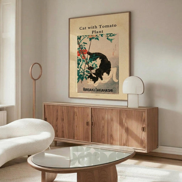 May include: Japanese woodblock-style poster print featuring black and white cat with tomato plant, mounted on cream-colored wall above walnut wood credenza. Modern living room setting with white curved chair, glass oval coffee table, and minimalist decor. Print shows vintage aesthetic with green foliage and red tomatoes against beige background.