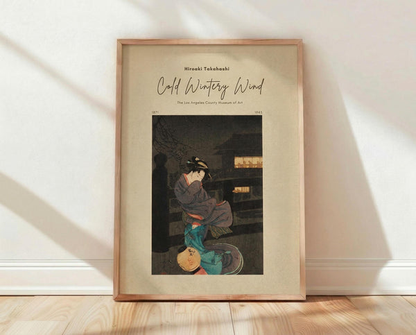 May include: Framed vintage Japanese woodblock print showing a woman in gray kimono sitting by a traditional structure during winter. The artwork features muted earth tones with teal accents and displays museum attribution text above the image. The print is mounted in a light wooden frame and positioned against white textured walls on blonde hardwood flooring with natural lighting creating soft shadows.
