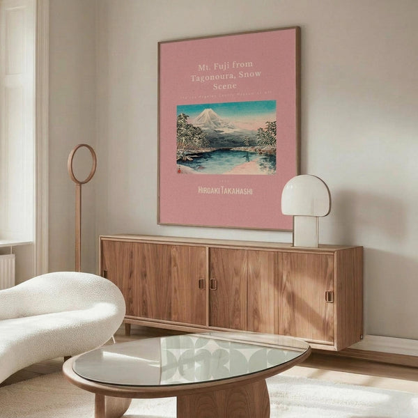 May include: Framed pink poster featuring Japanese woodblock print of snow-capped Mt. Fuji reflected in blue water, displayed above walnut credenza in modern living room with white curved chair, glass coffee table, and brass floor lamp