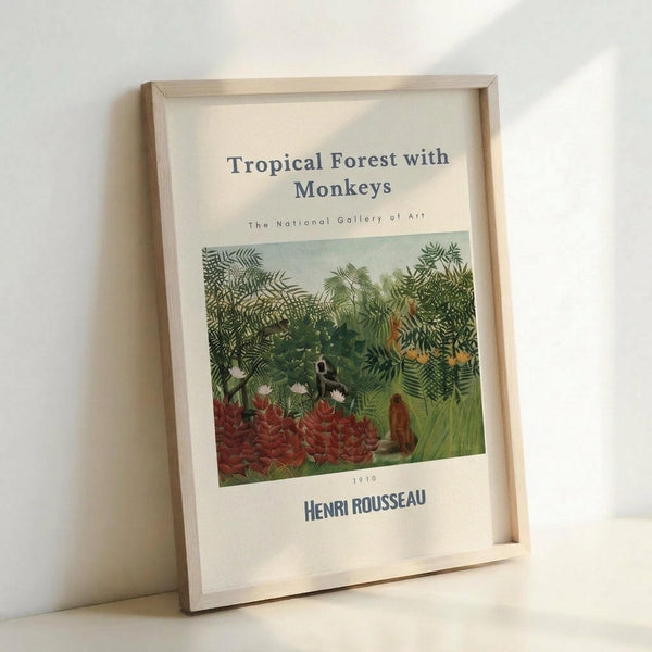 May include: Framed art print in natural wood frame leaning against white wall. Shows Henri Rousseau's lush tropical jungle scene with dense green foliage, red flowering plants, and hidden monkeys among the vegetation. Print has museum-style formatting with title, gallery attribution, artist name and date 1910. Frame appears medium-sized with light wood finish, casting soft shadow on wall.