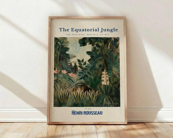 May include: Framed art print displayed against white wall on wooden floor. Print features lush tropical jungle scene with dense green foliage, palm fronds, and exotic plants in Henri Rousseau's distinctive naive style. Light wooden frame surrounds cream-colored poster with blue text reading "The Equatorial Jungle" and "Henri Rousseau 1909" along with "The National Gallery of Art." Natural lighting creates soft shadows on textured white wall.