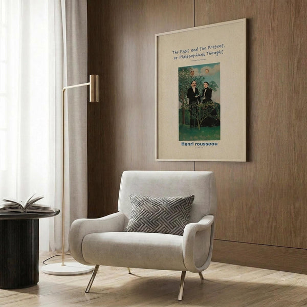 May include: Framed Henri Rousseau art print displayed on wood-paneled wall above cream upholstered armchair with geometric patterned pillow. The vintage-style poster features two figures in dark clothing against a lush green landscape with trees and foliage. Modern brass floor lamp with white base stands nearby next to dark round side table with open book. Soft natural lighting from window with sheer curtains.