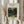 May include: Person in cream ruffled sleeves holding framed botanical art print and dried pampas grass against white curtained window. The vintage-style poster features lush green jungle foliage with monkeys and a red parrot, displayed in light wood frame with cream matting. Soft natural lighting creates gentle shadows on neutral walls.