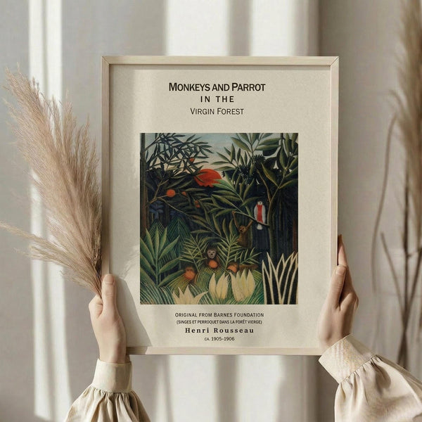 May include: Person in cream ruffled sleeves holding framed botanical art print and dried pampas grass against white curtained window. The vintage-style poster features lush green jungle foliage with monkeys and a red parrot, displayed in light wood frame with cream matting. Soft natural lighting creates gentle shadows on neutral walls.