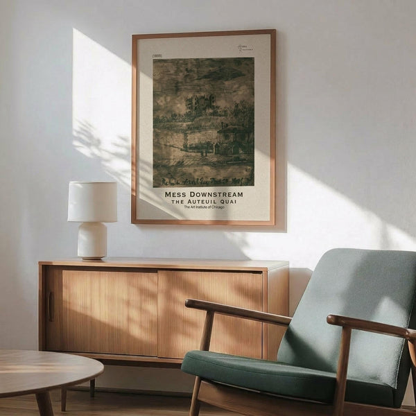 May include: Framed vintage art print displayed on white wall above wooden sideboard in modern living room. The artwork shows a muted green and brown landscape scene from 1865 with trees and buildings. Mid-century modern sage green armchair with wooden frame sits beside the credenza, along with white ceramic table lamp and round wooden coffee table. Warm natural sunlight creates geometric shadows across the scene.