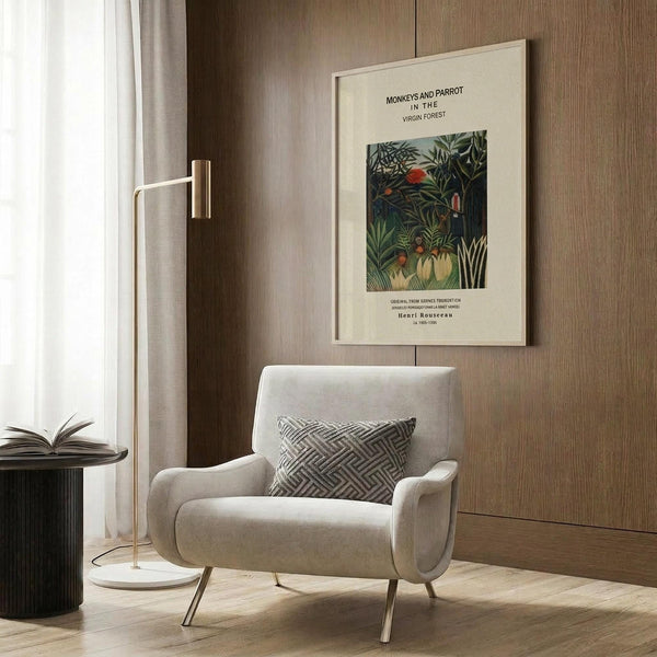 May include: Henri Rousseau jungle artwork print in cream mat and frame, mounted on wood-paneled wall above beige upholstered armchair with geometric patterned pillow. Golden brass floor lamp with white marble base stands nearby next to dark round side table with open book. Soft natural lighting from window with sheer curtains illuminates the modern neutral-toned interior setting.