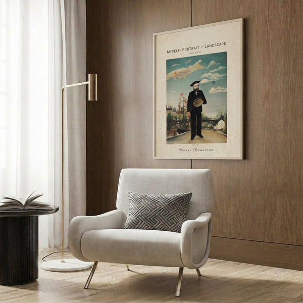 May include: Framed Henri Rousseau self-portrait print showing bearded man in dark suit holding palette against landscape with cloudy sky, displayed on wood paneled wall above cream upholstered armchair with geometric patterned pillow, brass floor lamp and dark side table with open book nearby