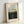 May include: Framed art print in light wood frame showing Henri Rousseau's jungle forest painting with bare trees, lush green foliage, and small figures in a clearing. The poster features museum-style white matting with "RENDEZVOUS IN THE FOREST" text, "The National Gallery of Art" attribution, and "1889" date. Frame leans against white wall on light surface with soft natural lighting.