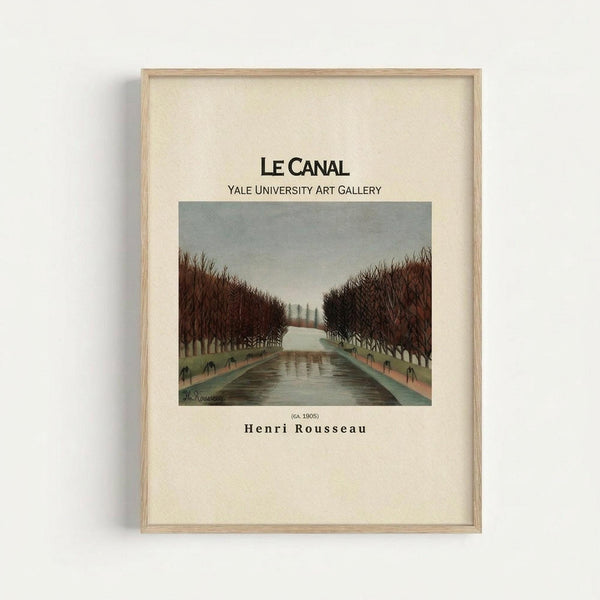A vintage art exhibition poster in a light wood frame hanging on a white wall. The poster features Henri Rousseau's painting of a tree-lined canal with bare winter branches creating a tunnel effect over dark water. The image shows muted colors - grey sky, brown trees, and olive-toned water. Text reads "LE CANAL" and "YALE UNIVERSITY ART GALLERY" above the artwork, with "Henri Rousseau" and "(CA. 1905)" below on cream-colored paper.