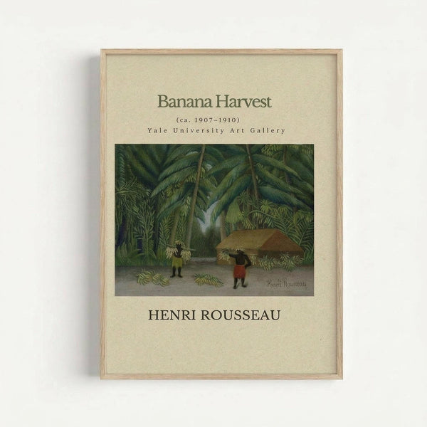 May include: Framed art print displaying Henri Rousseau's jungle painting with lush green palm trees and tropical foliage. Two small figures harvest bananas beneath the dense canopy. The vintage-style poster features cream colored matting with "Banana Harvest" and "Henri Rousseau" text, housed in a light wood frame against a white wall.