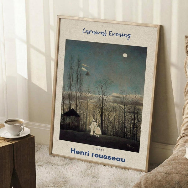May include: Framed art print leaning against white wall on textured rug beside wooden block with coffee cup. Print shows moonlit evening scene with bare winter trees, small figures in white clothing, and rustic building under dusky blue-green sky. Light wooden frame with cream matting. Cozy beige blanket visible at right edge.