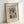 May include: Framed vintage Japanese woodblock print poster showing a snow-covered wooden bridge spanning a rocky winter gorge. The artwork features muted earth tones with white snow, displayed in a light wood frame against a white wall. The print includes museum attribution text at the top and artist signature at the bottom on cream-colored paper.