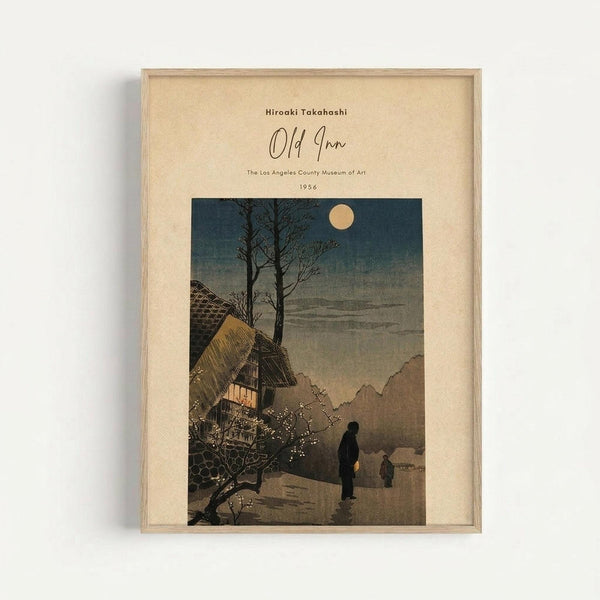 A framed vintage Japanese woodblock print depicting a moonlit winter evening scene with traditional thatched-roof buildings, bare trees, and silhouetted figures walking on a snowy path. The artwork features muted blue, gray, and brown tones with a full moon in the dark sky. The print is matted in cream-colored paper within a light wood frame and displayed against a white wall.