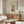 May include: Japanese woodblock print poster showing a white bird perched among plum tree branches in snow, displayed in a wood frame above a walnut credenza in a minimalist living room with white curved chair, glass coffee table, and modern floor lamp