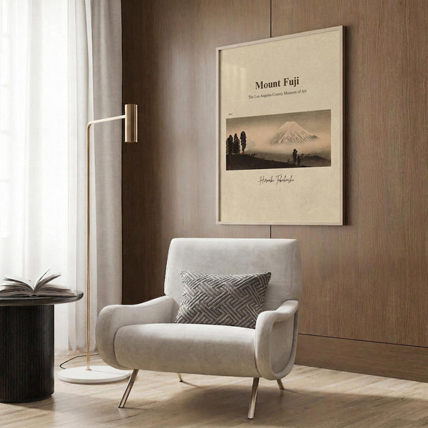 a cozy living room with a white armchair, a floor lamp, and a framed poster of Mount Fuji hanging on the wall.