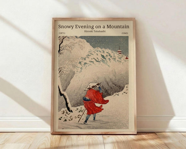 May include: Framed vintage Japanese woodblock print showing a figure in flowing red robes walking through heavy snowfall on a mountainous path. The artwork features muted earth tones with dramatic contrast from the bright red garment against snowy white mountains and dark evening sky. Traditional Asian art style with delicate linework and atmospheric perspective. Natural wood frame displayed on light wooden flooring against white wall with soft natural lighting creating gentle shadows.