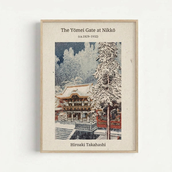 A framed vintage Japanese woodblock print showing a snow-covered temple gate at Nikko during winter. The artwork depicts the ornate Yomei Gate with traditional red and gold architecture, surrounded by snow-laden trees and falling snow against a dark blue sky. The print is matted in cream with text identifying the artwork and artist Hiroaki Takahashi, displayed in a light wooden frame against a white wall.