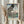 May include: Person in cream sweater holding framed Japanese woodblock print featuring large black carp kite with scaled pattern against blue sky, Mount Fuji and bridge landscape below. Light wood frame, dried pampas grass beside, soft window lighting creates warm interior styling scene.
