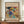 May include: A framed abstract art print displayed on a wooden sideboard against white paneled walls. The poster features vibrant swirling forms in blues, yellows, reds, and greens with dynamic brushstrokes and geometric elements. The print has cream matting and dark wood frame, with "The Art Institute of Chicago" and "Wassily Kandinsky" text. A small white ceramic vase and stacked books sit nearby on the warm wood surface.