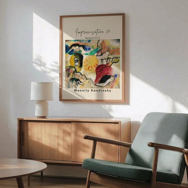 May include: Framed abstract art print displayed on white wall above wooden sideboard with table lamp. Green upholstered mid-century armchair with wooden arms sits nearby. The colorful abstract artwork features vibrant blues, yellows, reds and greens with flowing organic shapes. Natural sunlight creates dramatic shadows across the minimalist room setting with light wood furniture and neutral tones.