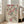 May include: Framed Japanese woodblock print featuring pink cherry blossoms, green willow branches, and colorful birds on cream background with Japanese text, displayed in light wood frame leaning against white wall next to beige upholstered chair in bright living room with large windows.