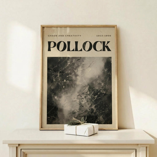 May include: Framed poster featuring Jackson Pollock's abstract expressionist drip painting in black and white tones, with "POLLOCK" text and "CHAOS AND CREATIVITY 1912-1956" at top. Natural wood frame sits on light wooden surface alongside small wrapped gift box with twine and greenery against cream wall.
