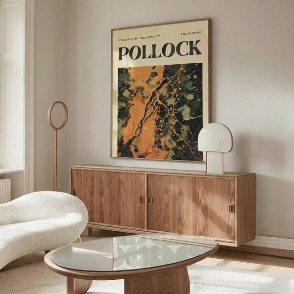 May include: Pollock exhibition poster with orange and dark green abstract paint splatter design hanging above wooden mid-century credenza in modern living room. White curved chair and glass coffee table visible in foreground, with minimalist table lamps on sideboard.