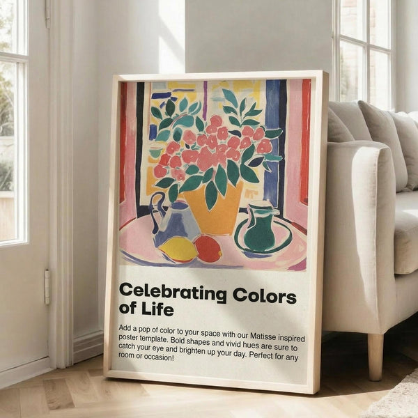 May include: Framed poster featuring Matisse-inspired still life with orange vase holding red flowers, green leaves, blue teapot, green pitcher, and yellow and red fruits on pink table. Colorful artwork with bold shapes in living room setting next to beige sofa near windows. Text reads "Celebrating Colors of Life" with descriptive copy below the vibrant illustration.