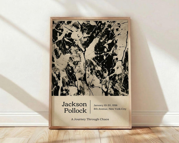 May include: Framed poster featuring Jackson Pollock's abstract black paint splatters and drips on cream background, with exhibition text below reading "Jackson Pollock January 10-20, 1956 8th Avenue, New York City A Journey Through Chaos." Natural wood frame leans against white wall on light wooden floor with soft shadows.