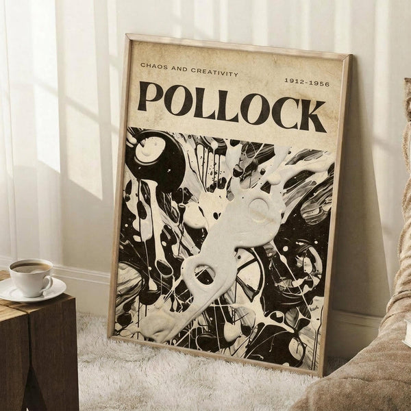 May include: Framed vintage-style poster displaying abstract black and white paint splatters and drips in Jackson Pollock's signature style, with "CHAOS AND CREATIVITY" and "POLLOCK 1912-1956" text at top. Poster leans against white wall in cozy room setting with coffee cup on wooden side table and textured beige throw blanket visible.