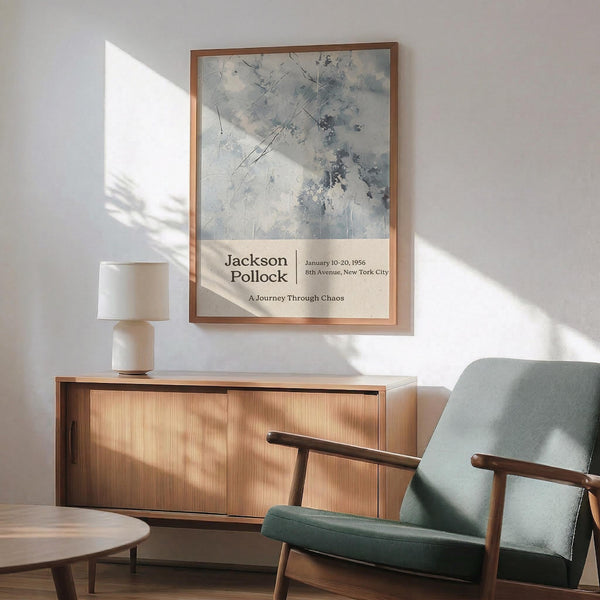 a wooden cabinet with a lamp on top, and a green armchair in the foreground. The cabinet has a white lamp on it, and the armchair has a green cushion. Above the cabinet, there is a framed poster hanging on the wall.