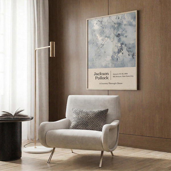 a modern living room with a white armchair, a floor lamp, and a framed poster on the wall.