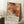 May include: Abstract art poster with vibrant orange, red, and black paint splatters and white linear elements in light wood frame, leaning against white wall corner next to beige armchair and wooden side table with white coffee cup on saucer, displayed on white textured rug in bright natural lighting.