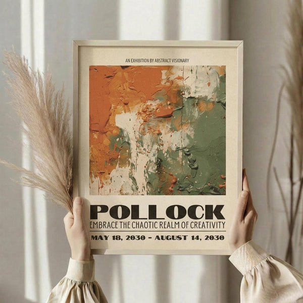 May include: Person in cream blouse holding framed abstract art poster featuring Jackson Pollock-style paint splatters in orange, green, and white. Poster has exhibition text and dates, displayed in light wooden frame. Dried pampas grass visible to left, neutral curtained background creates soft, artistic home setting.
