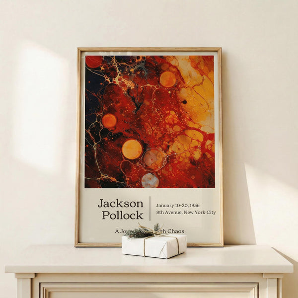 May include: Jackson Pollock exhibition poster mockup in natural wood frame, featuring abstract artwork with vibrant red, orange, yellow and black paint splatters and circular forms. Poster displays exhibition details and "A Journey Through Chaos" text below artwork. Frame leans against white wall on light wooden shelf next to small white wrapped gift with twine and evergreen sprig.