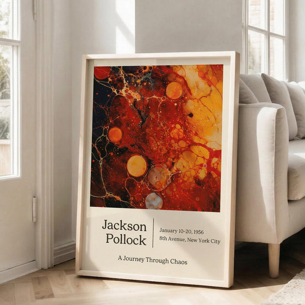 May include: Abstract artwork poster in white frame leaning against white wall next to beige sofa. Features vibrant red, orange, and yellow fluid paint with black marbled areas, circular bubble patterns, and flowing organic shapes. Exhibition-style design with "Jackson Pollock" text, dates, and "A Journey Through Chaos" subtitle below the colorful abstract composition.