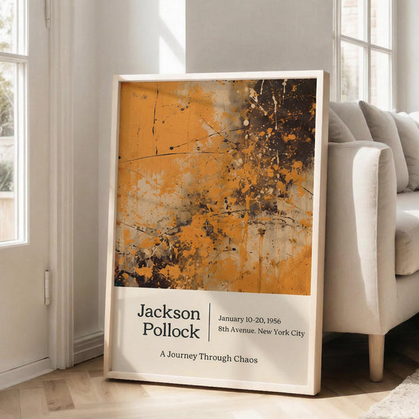 May include: Framed Jackson Pollock exhibition poster with abstract orange and brown paint splatter artwork, leaning against white wall next to beige upholstered sofa in bright room with large windows. Poster features vibrant orange background with dark brown paint drips and splatters, exhibition text below artwork, contained in thin light wood frame on hardwood floor.