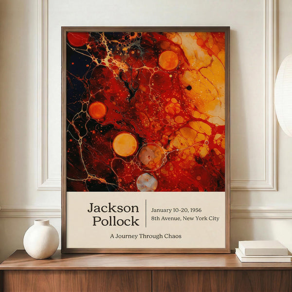 May include: Abstract art poster with vibrant red, orange, yellow and black paint splatters and circular forms in Jackson Pollock's drip painting style, displayed in brown frame on wooden credenza beside white ceramic vase and stacked books in elegant room with cream walls and white molding.