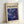 May include: Framed poster featuring swirling blue and purple abstract design with yellow and white circular dots scattered throughout, resembling a cosmic or fluid marble pattern. The print has "POLLOCK" in large black letters at the top with "CHAOS AND CREATIVITY 1912-1956" in smaller text. Light wood frame displayed leaning against white wall on white surface, creating subtle shadows.