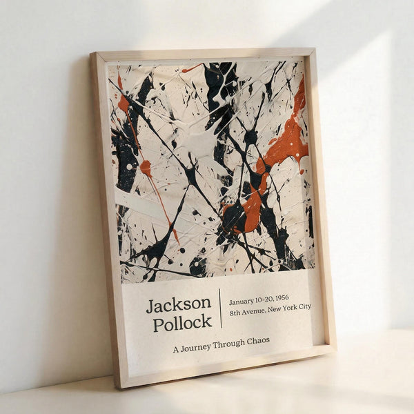 May include: Framed abstract expressionist poster featuring black paint splatters and drips with orange-red accents on cream background, displayed in light wood frame against white wall. Text below artwork reads "Jackson Pollock" with exhibition details and "A Journey Through Chaos" subtitle.