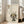 May include: Framed poster print featuring a cute black cat with large yellow eyes and rosy cheeks sitting beside green bamboo stalks, with Japanese characters at top, displayed on light wooden floors next to a beige upholstered chair in a bright room with white walls and windows