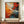 May include: Abstract expressionist poster with vibrant orange, red, blue and black paint splatters and drips displayed in brown frame on wooden credenza. White ceramic vase and stacked books sit nearby. Features bold brushstrokes, paint drops, and dynamic color bursts against cream background with "POLLOCK Expressive Expressionist Movement" text at bottom.