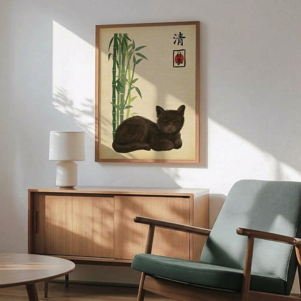 May include: Framed poster featuring a dark brown cat resting beside green bamboo stalks on cream background with Japanese characters and red stamp. Shown hanging above wooden credenza with white ceramic lamp in modern living room with mint green upholstered chair and round wooden coffee table. Natural sunlight creates geometric shadows on white wall.